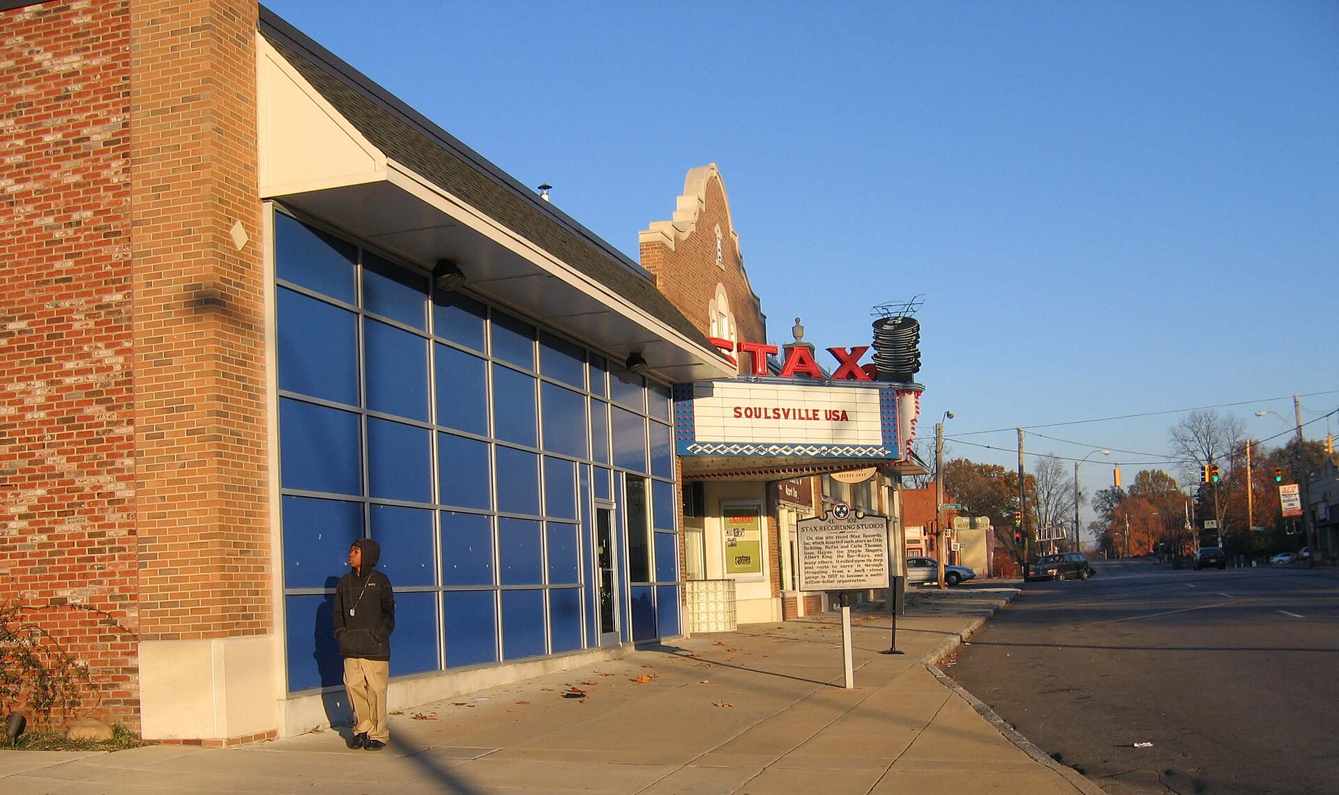 Stax marquee reading "Soulsville USA" on a brick and blue-glass building, with a person waiting on the empty sidewalk