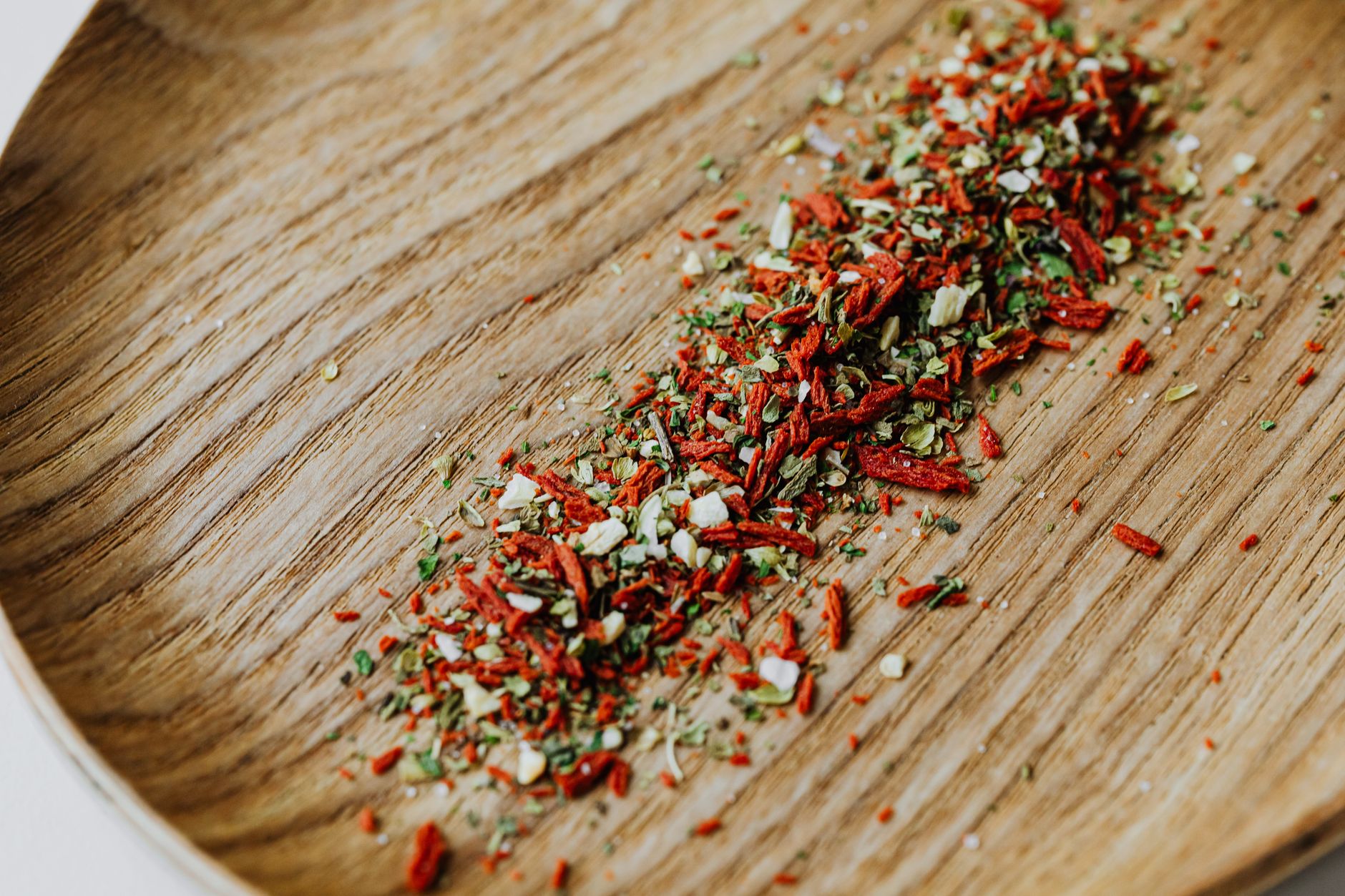 Close up of vibrant dried herbs and spices scattered on a wooden board