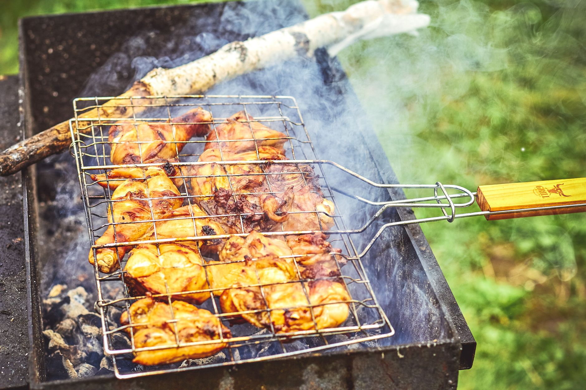 Close up of grilled chicken on an outdoor barbecue, emitting smoke and flavor