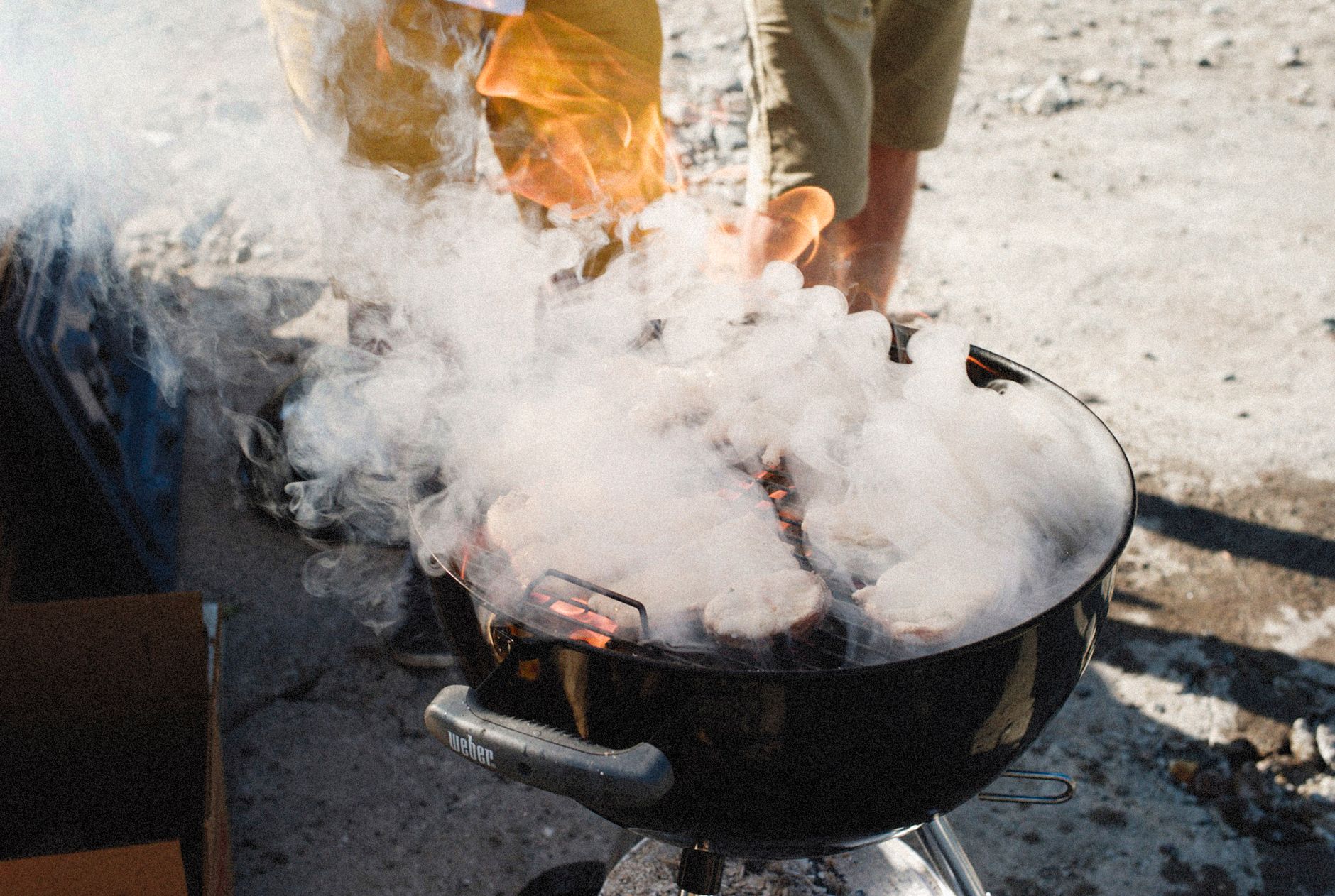 Grilling meat on a smoky barbecue grill outdoors on a sunny day