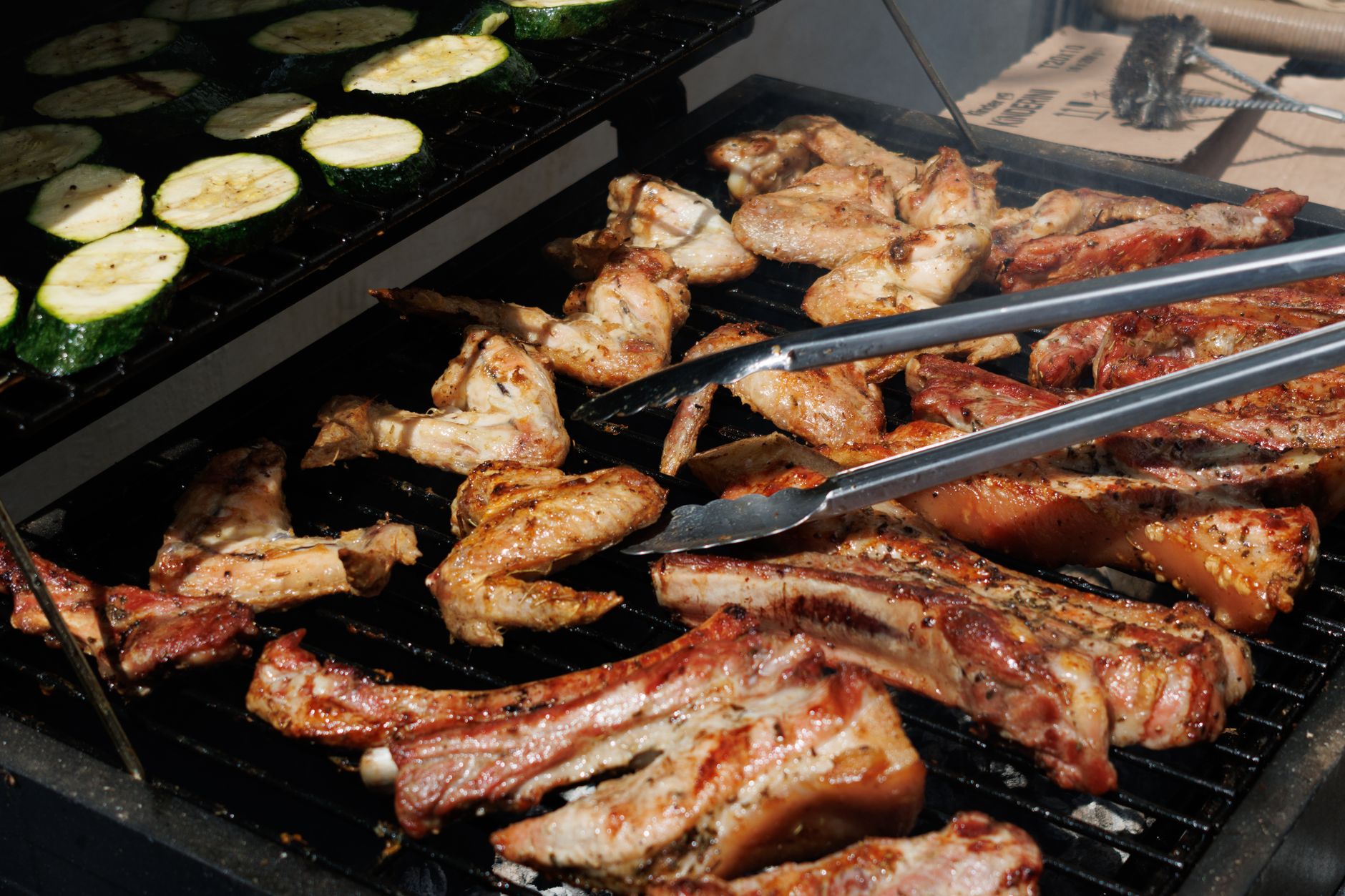 Barbecue chicken and zucchini grilling outdoors on a sunny day
