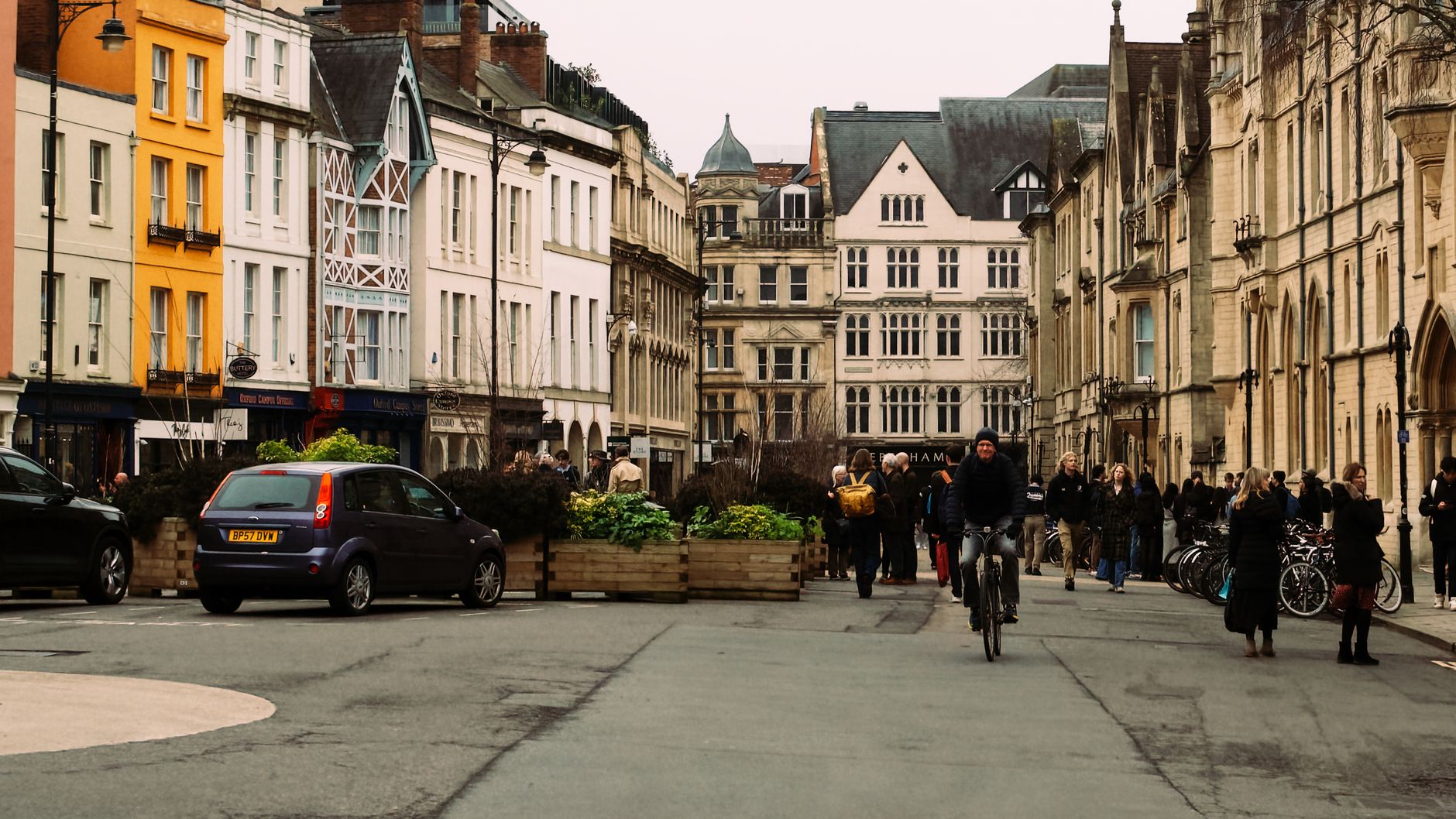 A lively day on an Oxford street with people and a cyclist amidst historic architecture
